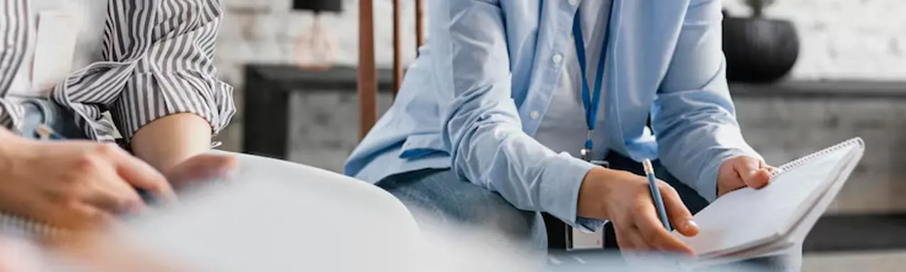 Mental health professional conducting a clinical assessment through conversation and note-taking