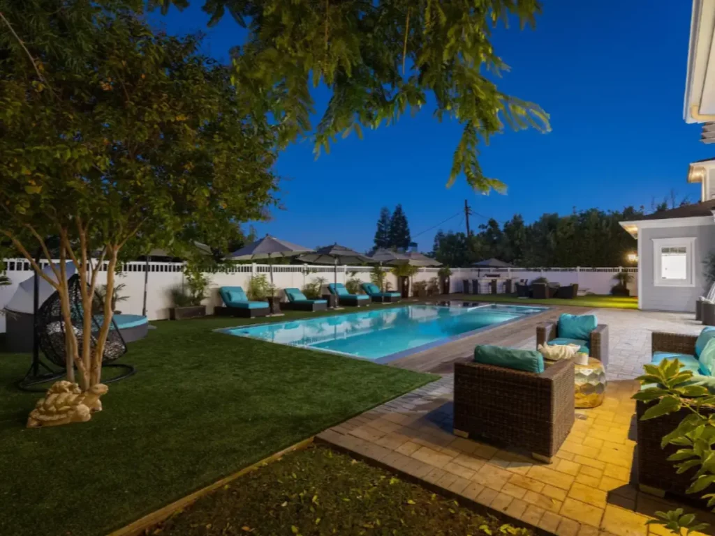 Luxury outdoor pool and lounge area at Legacy Healing Center in Los Angeles, featuring comfortable seating, umbrellas, greenery, and a serene nighttime setting for athletes’ recovery.
