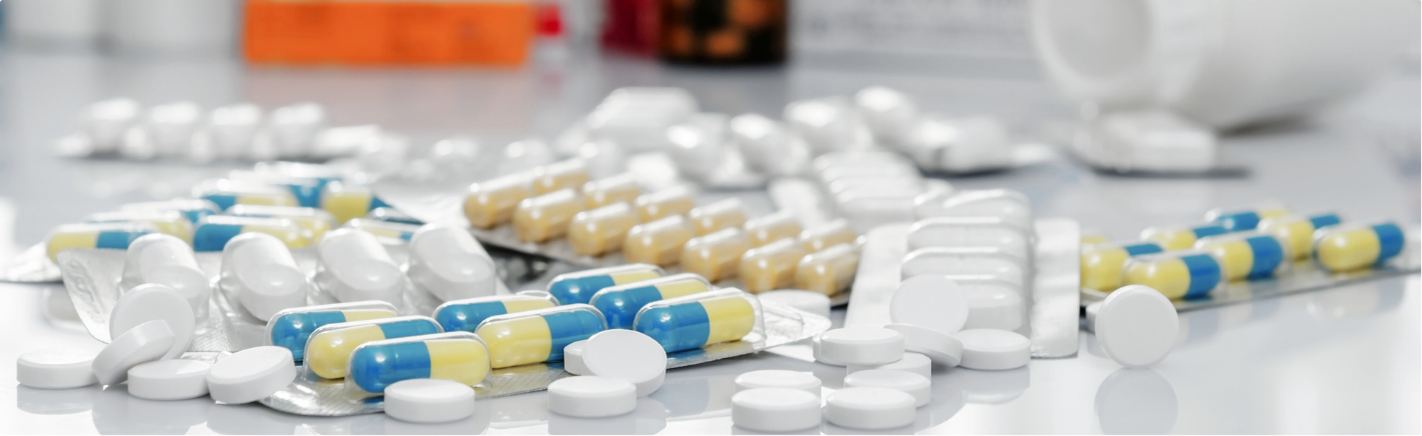 Assorted prescription pills and capsules scattered around blister packs and pill bottles.