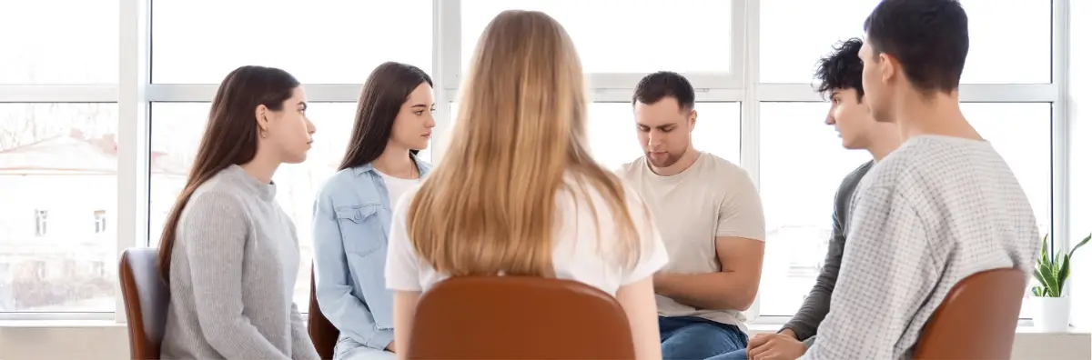 Small group of young adults sitting in a circle for a support group session.