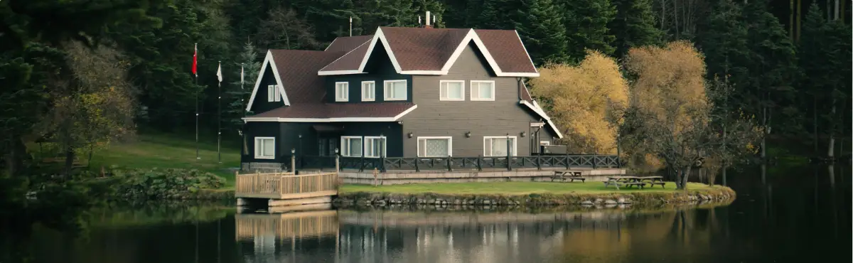 Large home by a lake surrounded by trees, representing a peaceful sober living environment.