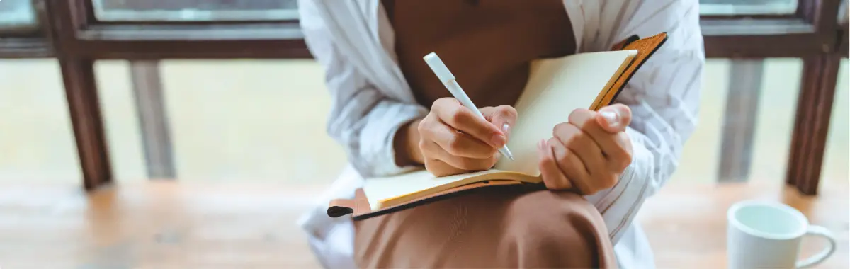 Person journaling in a notebook, representing reflection and recovery in sober living.