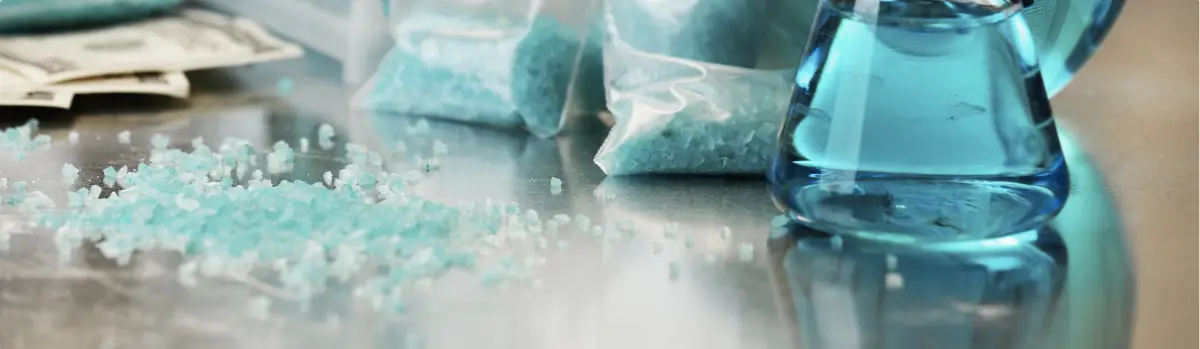 Meth, a blue crystal-like substance and baggies on a table.