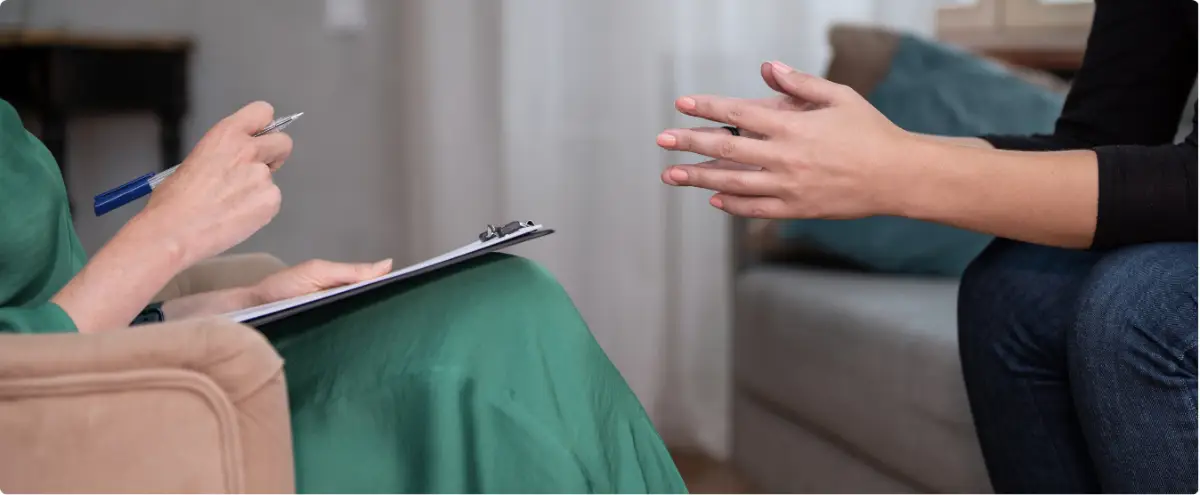 Client speaking with a clinician holding a clipboard, representing holistic support and personalized care during detox.