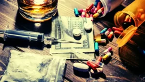 Assortment of street drugs, pills, syringe, and alcohol showing poly-substance addiction risk